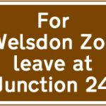 Exit from a motorway at a junction ahead that should be used for a tourist attraction