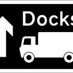 Motorway junction ahead leading to a route advised for goods vehicles to the destination shown, which may differ from that for other traffic