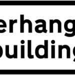 Reduced headroom over part of road due to overhanging building ahead
